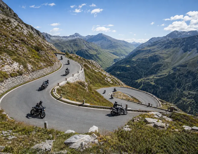A group of riders carving down an alpine pass